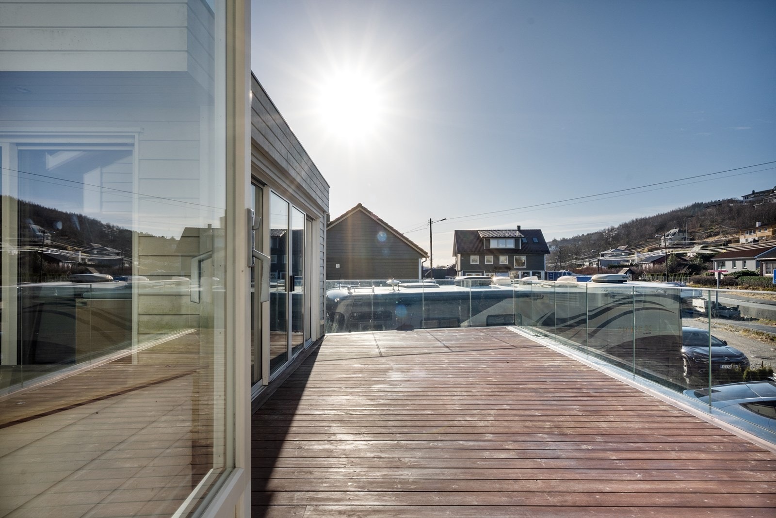 Stor solrik terrasse med glassrekkverk og hagestue med skyvedører Galleribilde