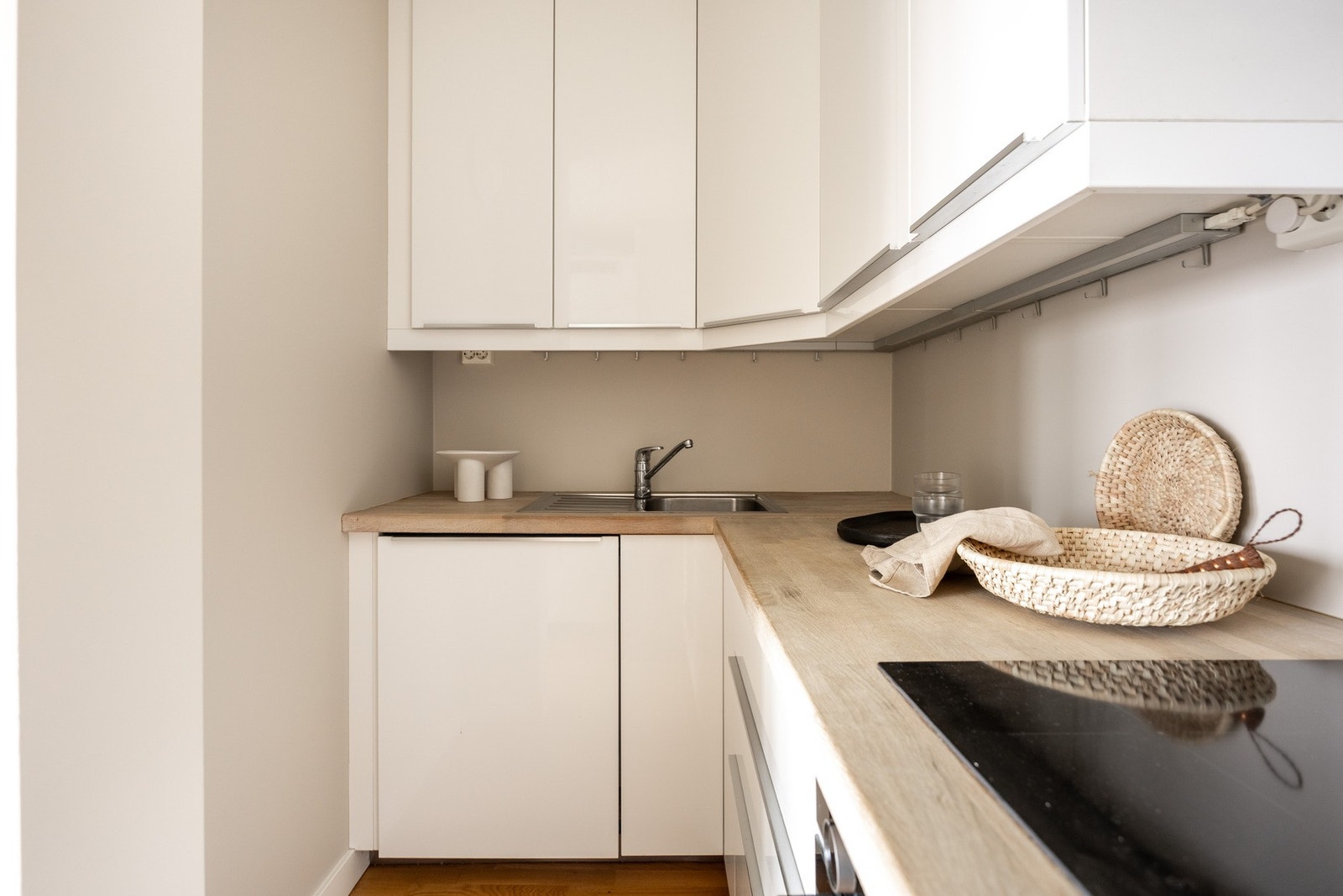 Pent Ikea kjøkkeninnredning fra 2010 med slette fronter og enkel belysning over heltre benkeplate. Galleribilde