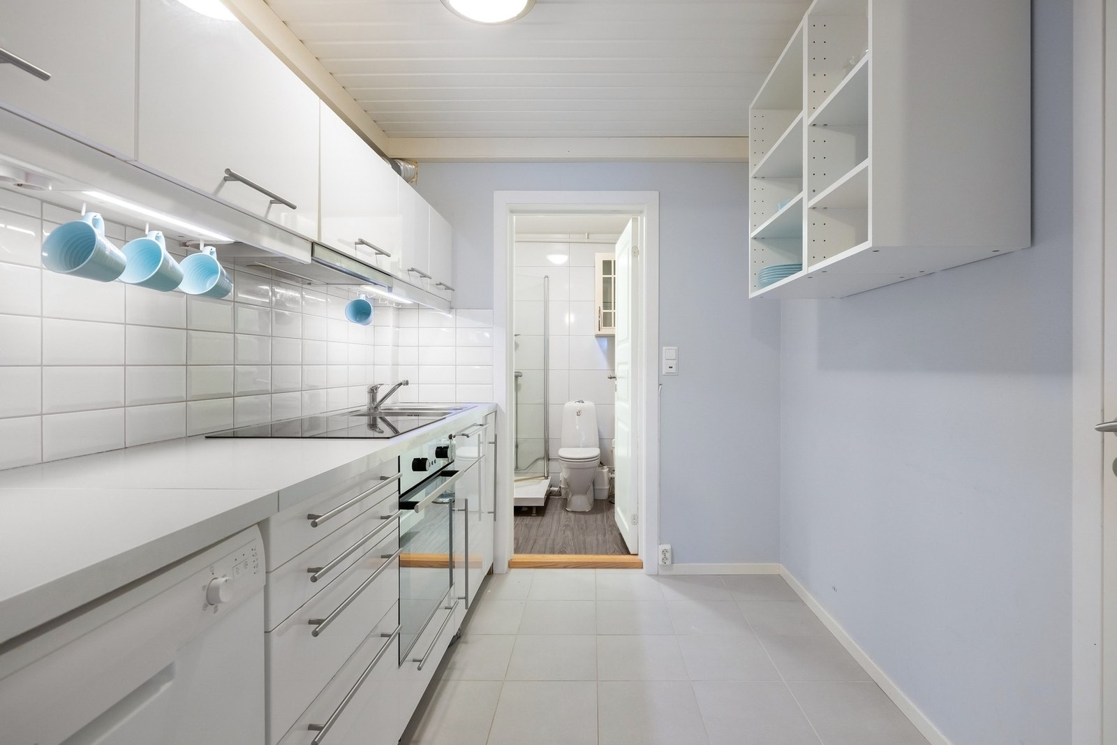 Kjøkken separat del. Innredning med glatte malte fronter, laminat benkeplate med nedfelt vaskekum og platetopp. Oppvaskmaskin og integrert stekeovn og frittstående kjøleskap. Ventilator i overskap med avtrekk ut. Galleribilde