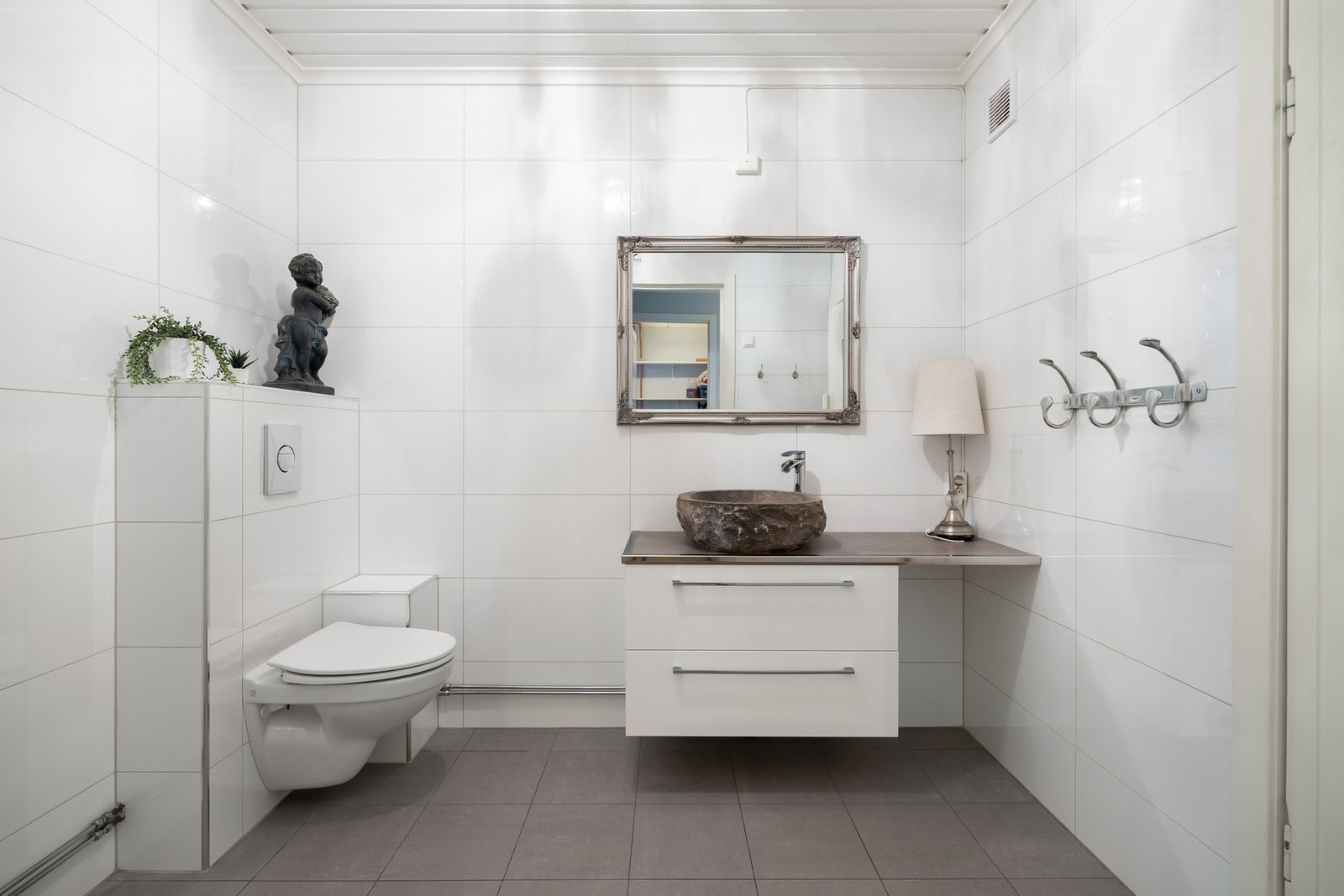 Baderom med flislagte vegger og gulv med varmekabler. Servantinnredning med brede skuffer og frittstående servant. Galleribilde