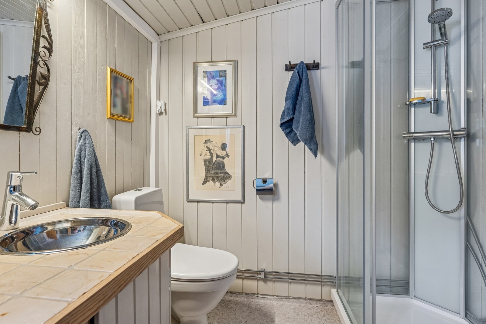 Bad har montert klosett, servant og dusjkabinett. Servantskapet er plassbygd i trepanel med flislagt benkeplate og oppbevaring i underskap Galleribilde