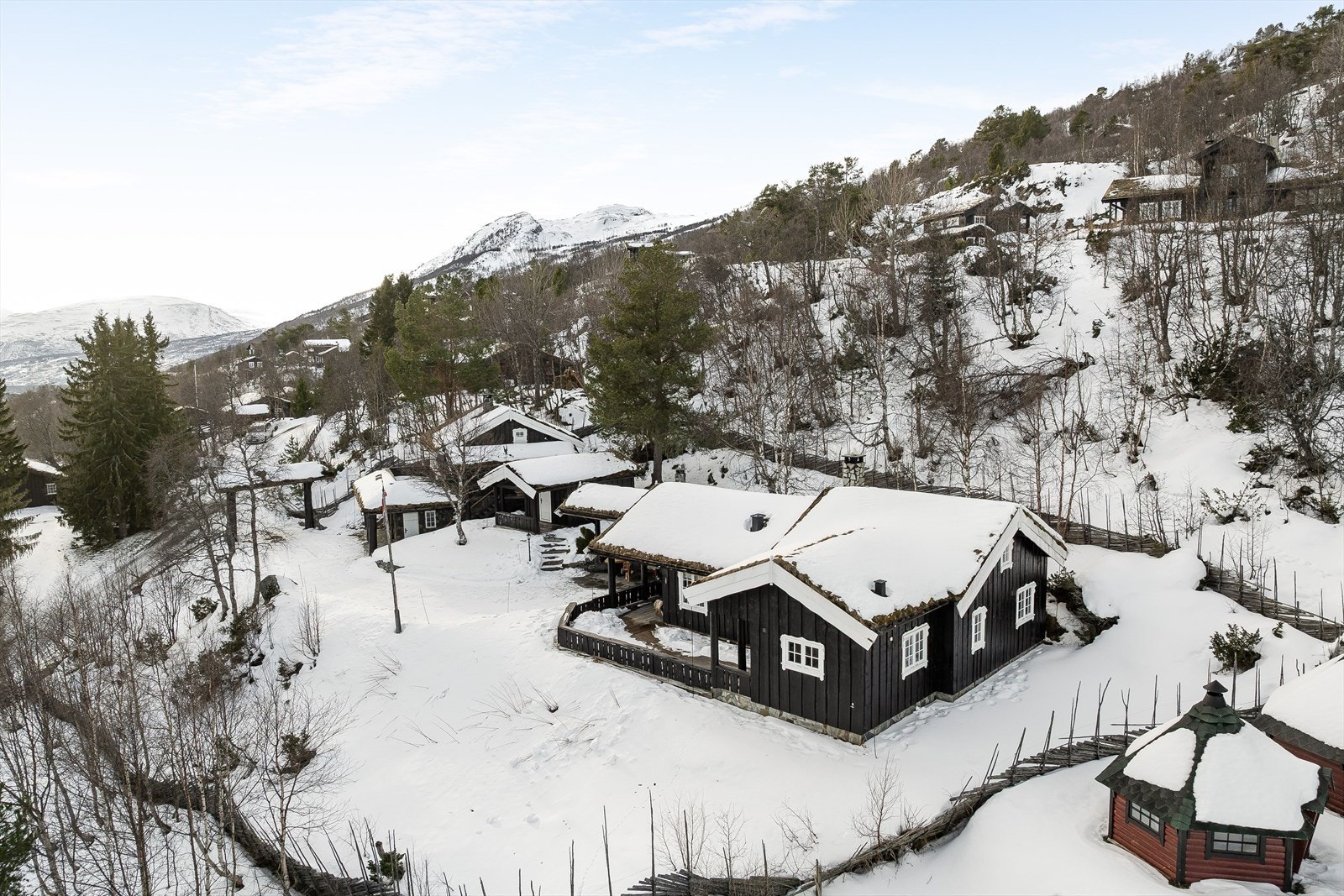 Ved ankomst til eiendommen passeres en port som markerer inngangen til området. Tomten er inngjerdet med tradisjonell skigard, som gir en vakker og tidløs ramme rundt det private tunet. Galleribilde