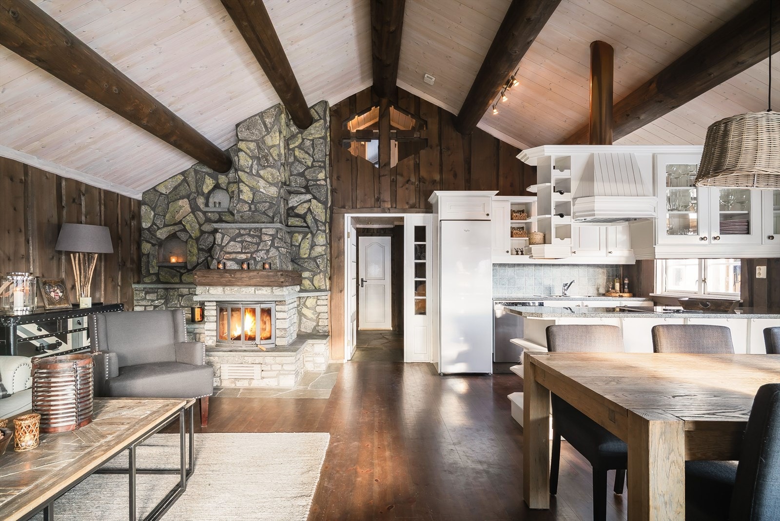 Allrommet preges av høy takhøyde, mørke, varme materialer og en elegant skiferpeis. Galleribilde