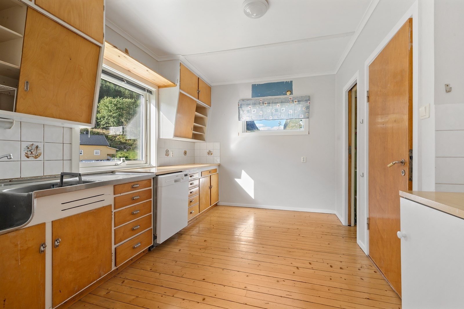 Kjøkkenet har innredning fra byggeåret med laminert benkeplate og stål oppvaskkum. Galleribilde