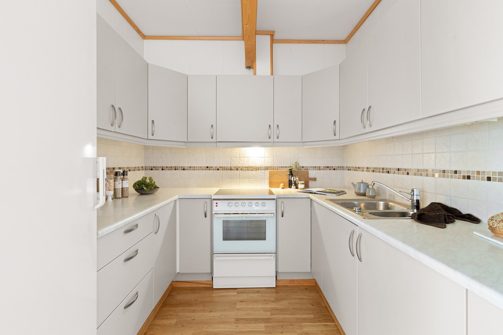 Kjøkkenet har slette fronter og benkeplate i laminat. Her er det plass til frittstående hvitevarer som komfyr og kjøleskap, men det er verdt å nevne at oppvaskmaskin ikke er inkludert. Galleribilde