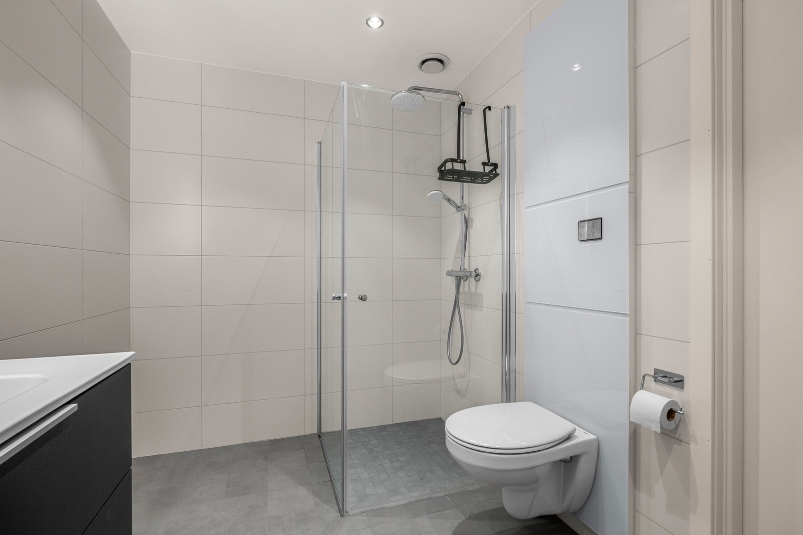 Badet har innfellbare dusjdører, vegghengt toalett, og baderomsinnredning med store skuffer. Galleribilde