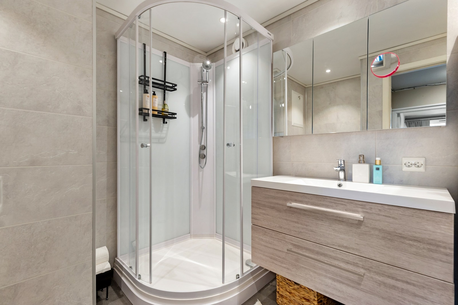 Badet er utstyrt med vegghengt toalett, dusjkabinett, servantinnredning og opplegg for vaskemaskin. Galleribilde