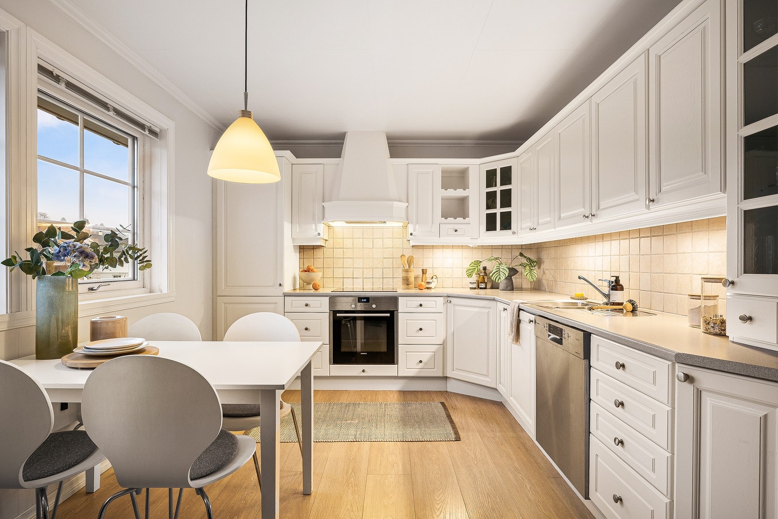 Kjøkkeninnredningen fra Mørekjøkken består av en kombinasjon av slette og heltre, malte profilerte fronter, samt to skap med glassfronter. Benkeplaten er i laminat med underlimt vaskekum i stål Galleribilde