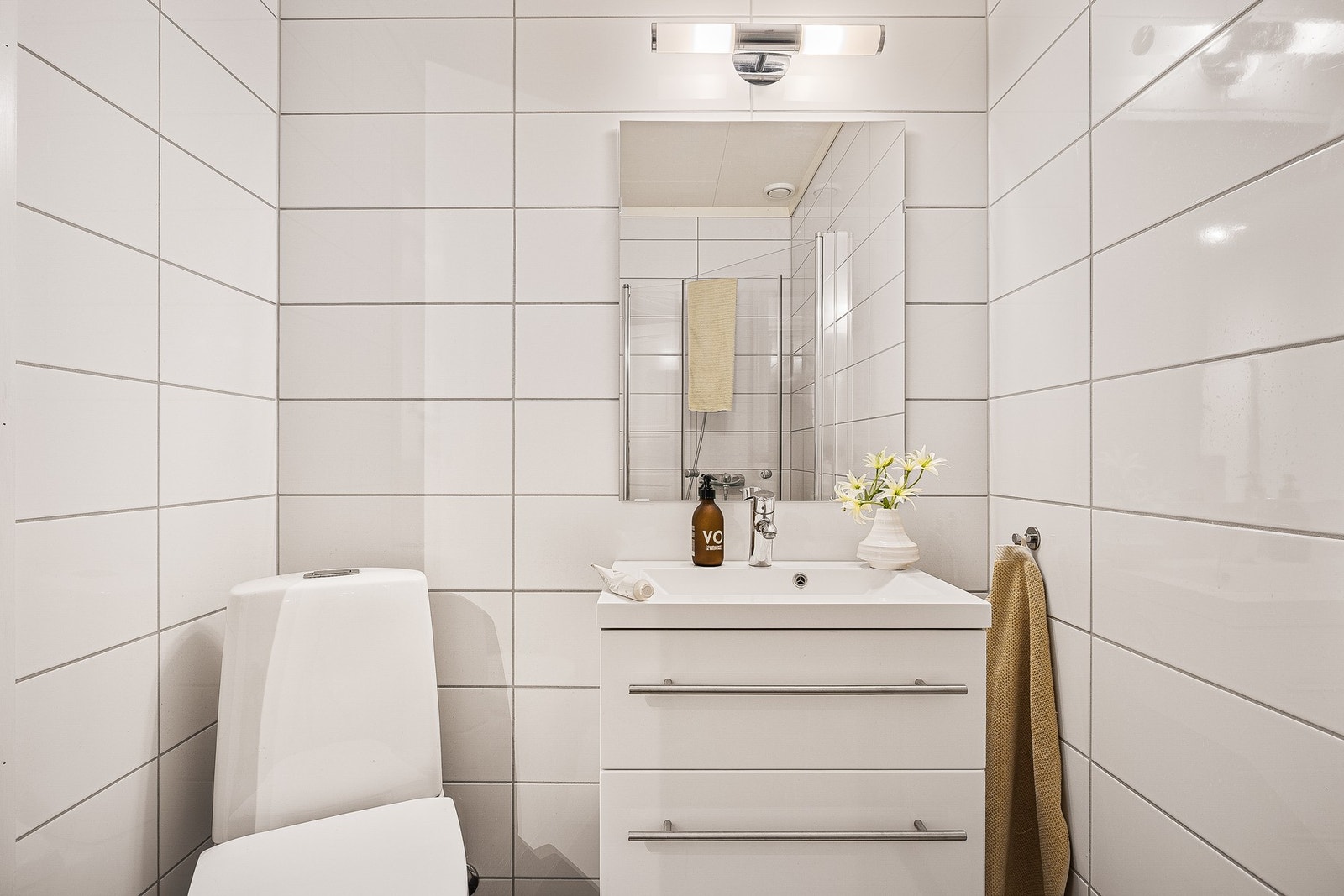 Badet er innredet med servant med tilhørende baderomsmøblement, speil og belysning. Videre inneholder rommet toalett samt innfellbart dusjhjørne i glass med tilhørende dusjgarnityr. Planløsningen er arealeffektiv og tilpasset rommets størrelse Galleribilde