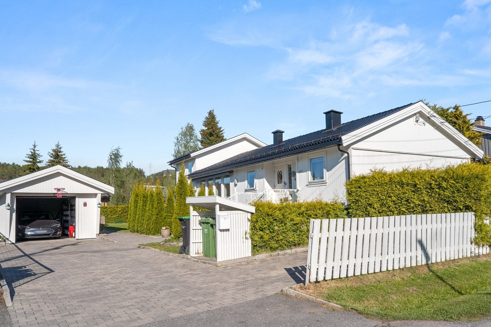 Stor, steinbelagt gårdsplass med parkering for flere biler i tillegg til garasjen. Galleribilde