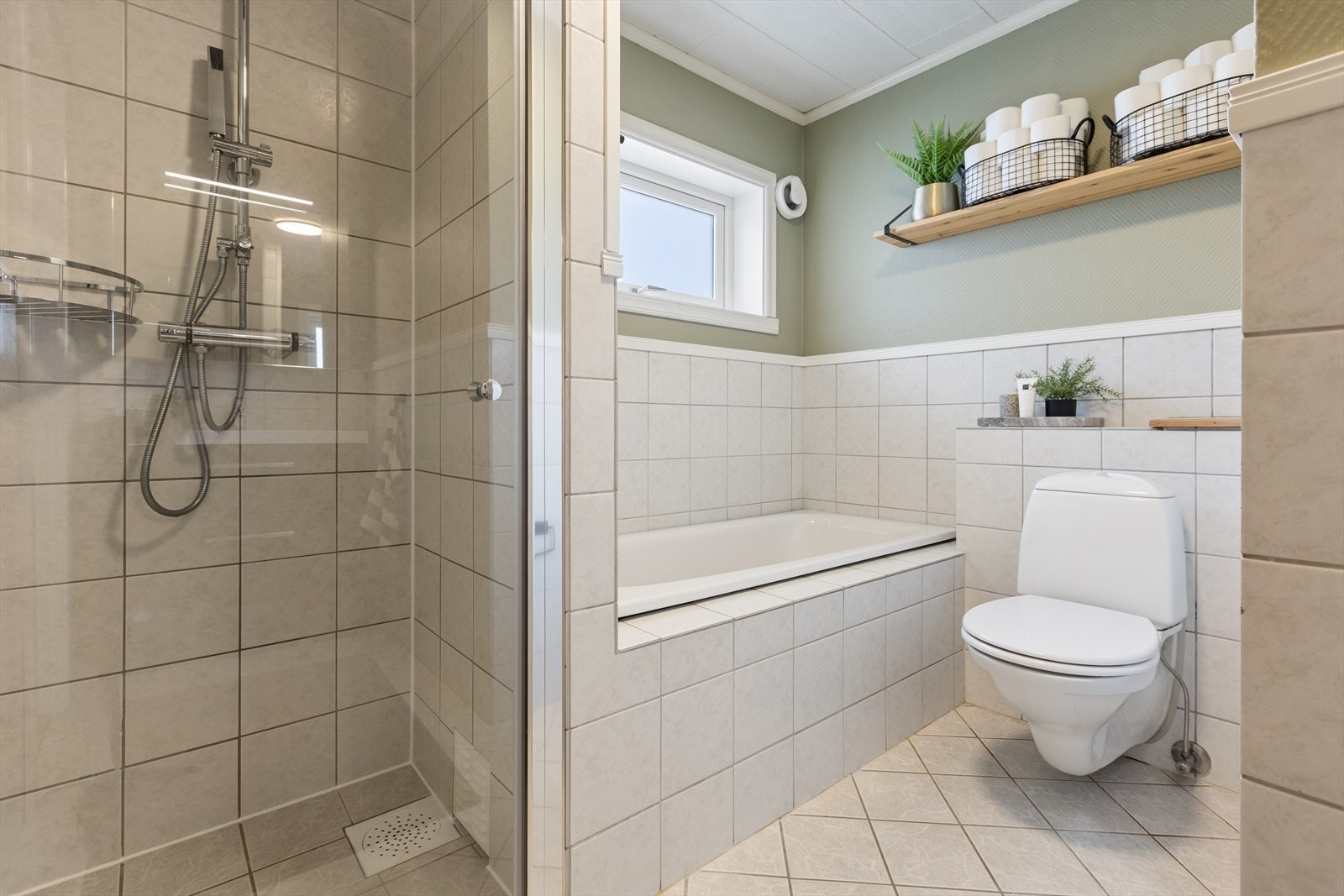 Lyst og pent flislagt bad med dusjhjørne og et herlig badekar. Galleribilde