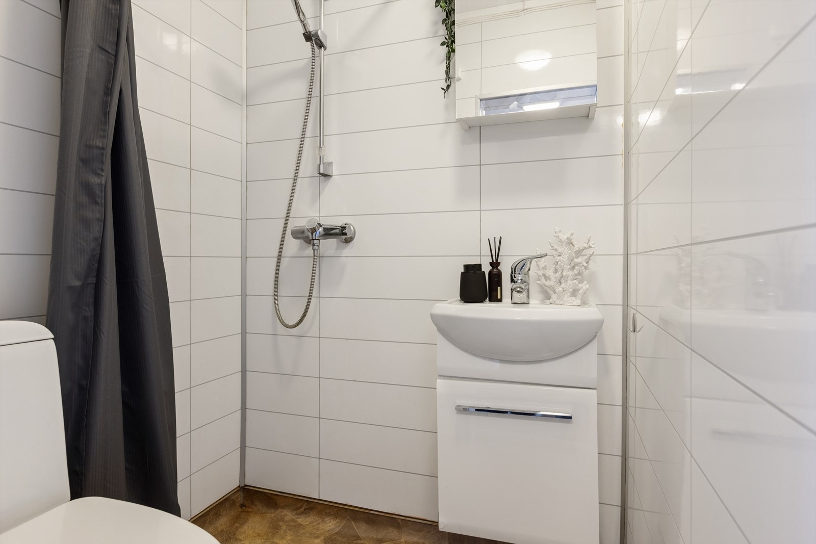 Badet er lyst og er utstyrt med dusjhjørne, gulvstående toalett og en lys og moderne baderomsinnredning. Galleribilde