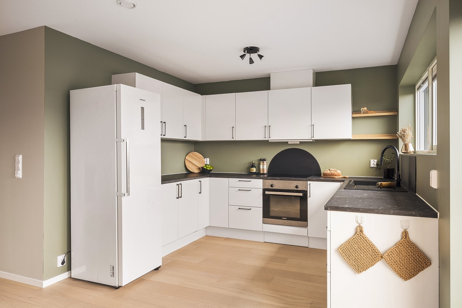 Kjøkkeninnredning med slette fronter som inneholder laminert benkeplate, kompositt vaskekum, ventilator, waterguard og komfyrvakt. Galleribilde