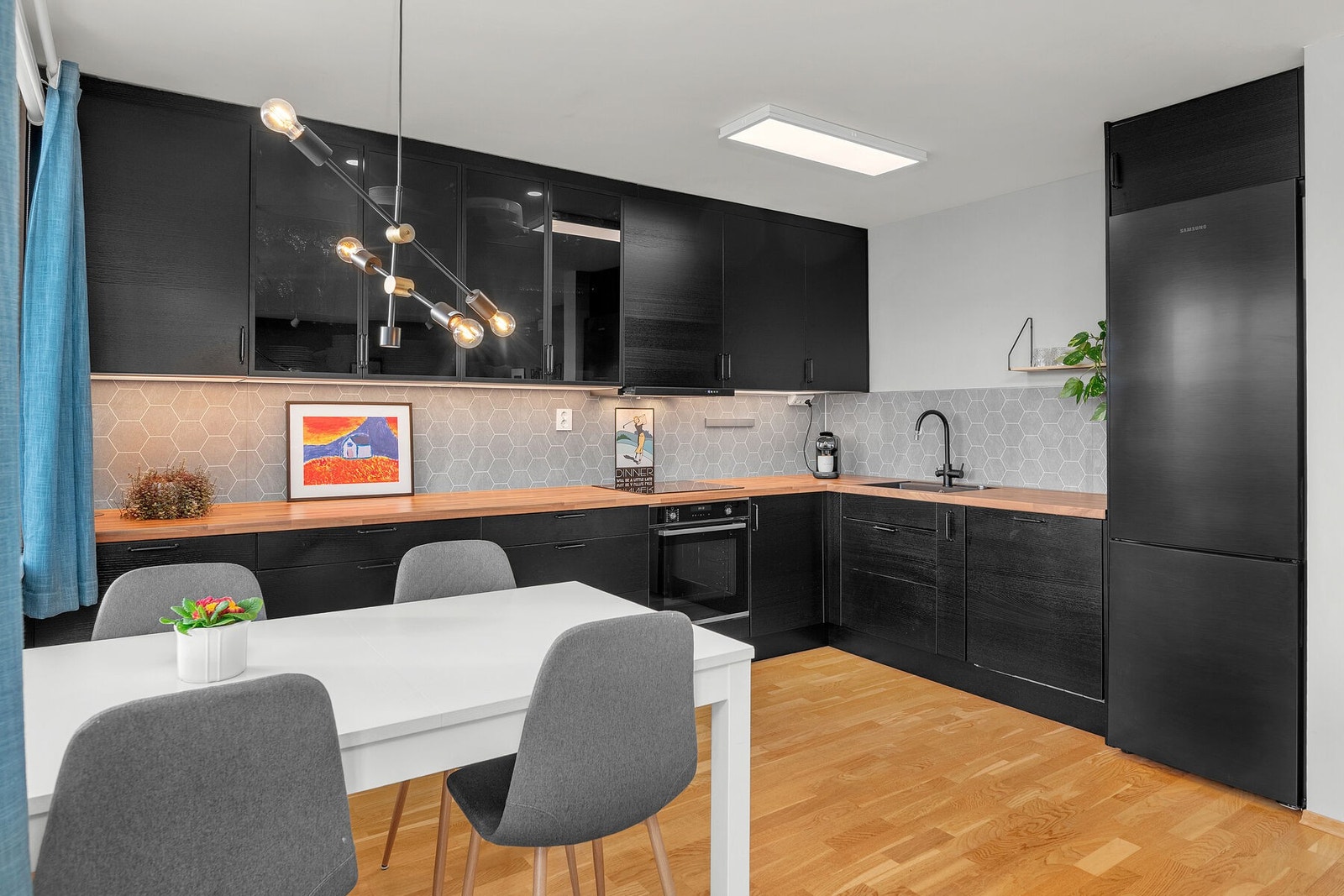 Stilrent kjøkken fra 2022 som fungerer som et blikkfang i stuen. God skap- og benkeplass, samt enkelte overskap i glass med integrert belysning. Galleribilde