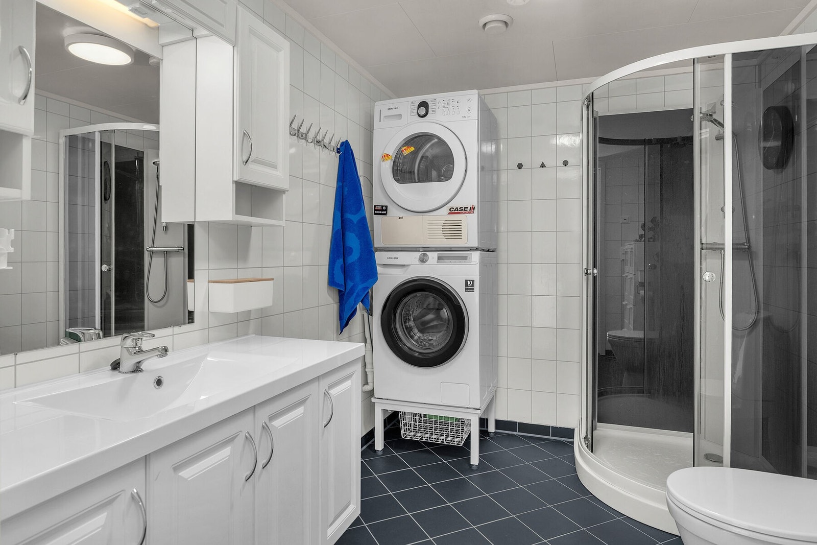 Tidløst flislagt bad/vaskerom med varmekabler i gulv. Innredet med servant, toalett og dusjkabinett. Opplegg for vaskemaskin. Galleribilde