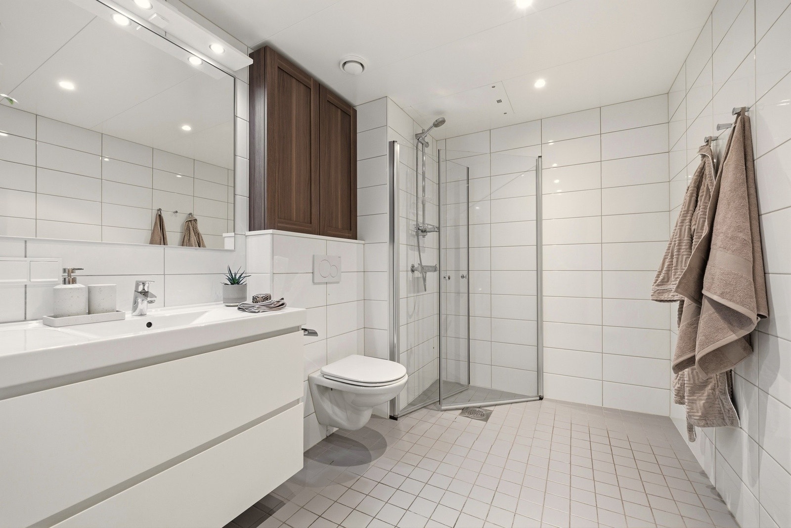 Badet er flislagt i blanke, lyse toner. Galleribilde