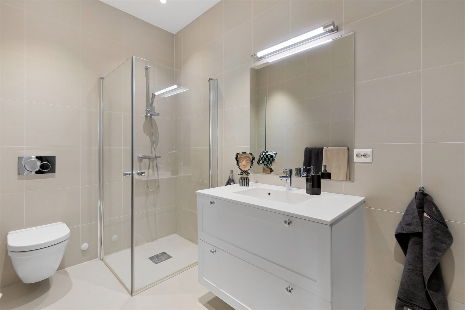 Bad pusset opp i 2015. Nedsenket dusjhjørne med dører i herdet glass, heldekkende servant med underskuffer og vegghengt toalett. Galleribilde