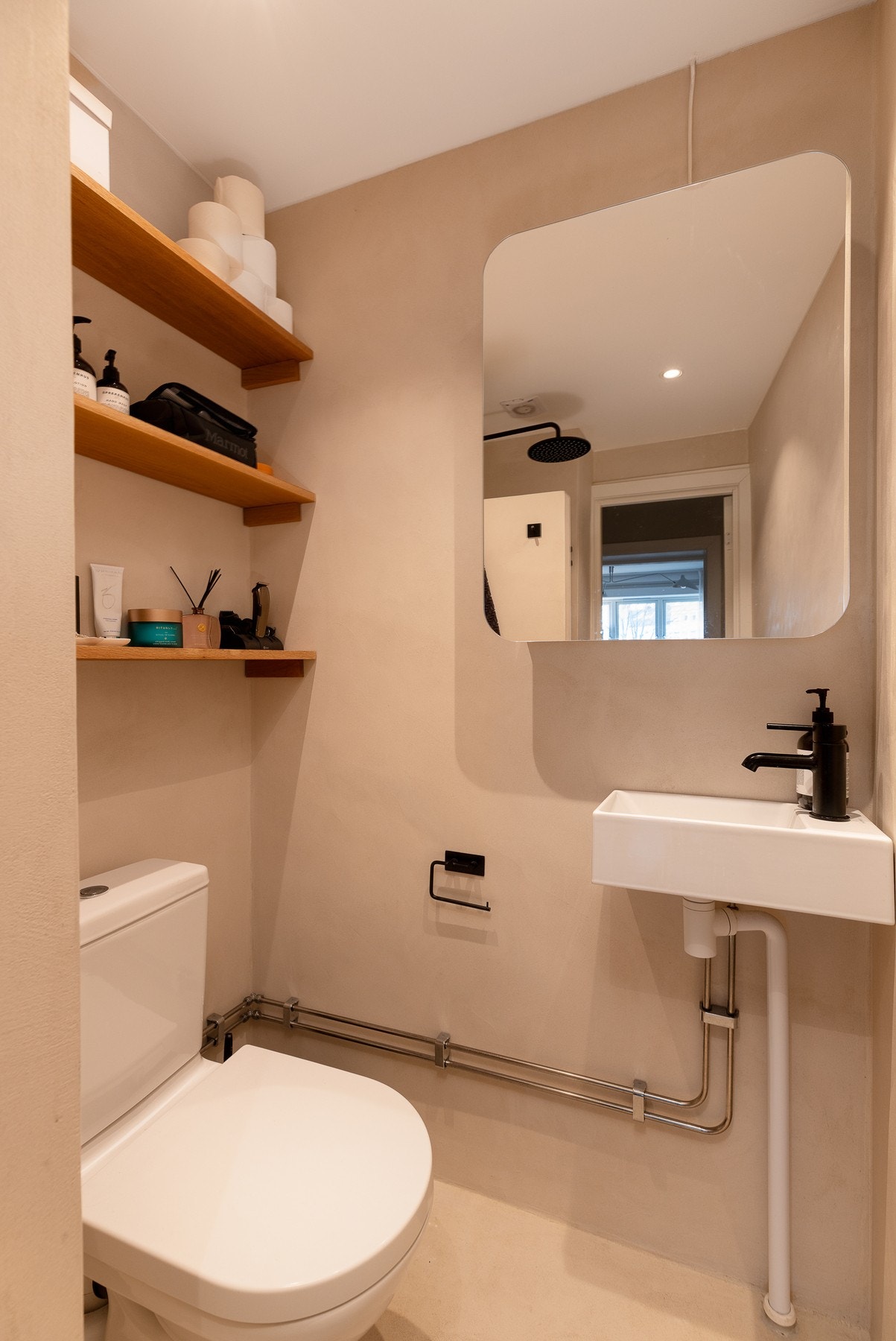 Badet har varmekabler, dusj med dusjvegg, servant, lekre trehyller til oppbevaring og WC. Galleribilde