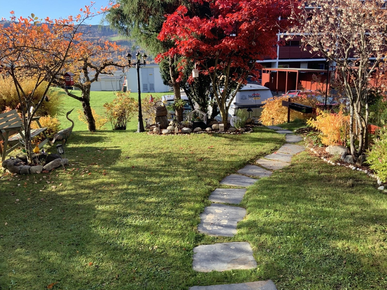 hage utenfor leiligheten er pent opparbeidet med plen, beplantning og gangstier. Galleribilde