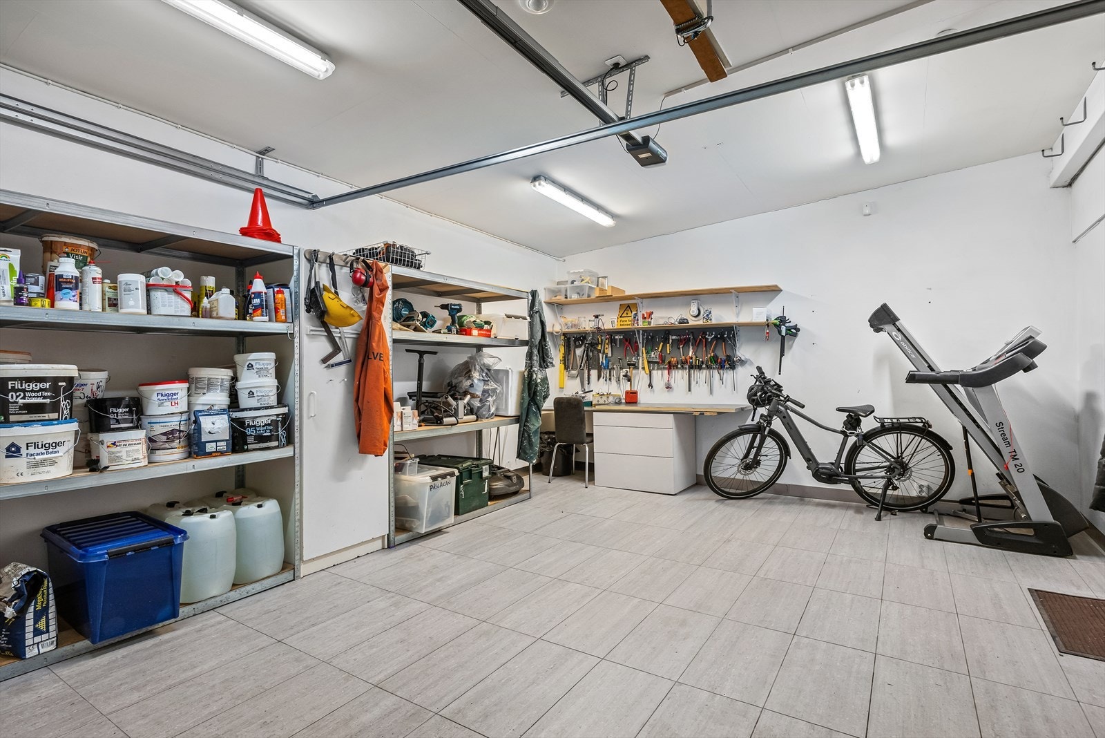 En stor og flislagt garasje med hyller som følger med salget Galleribilde