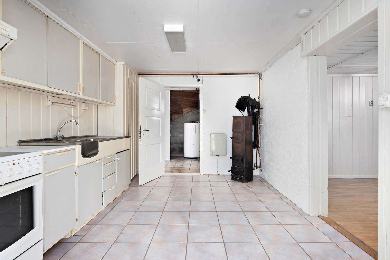 Det er et kjøkkenet i underetasjen med enkel utforming. Eldre innredning med folierte skrog, slette fronter og laminert benkeplate. Galleribilde