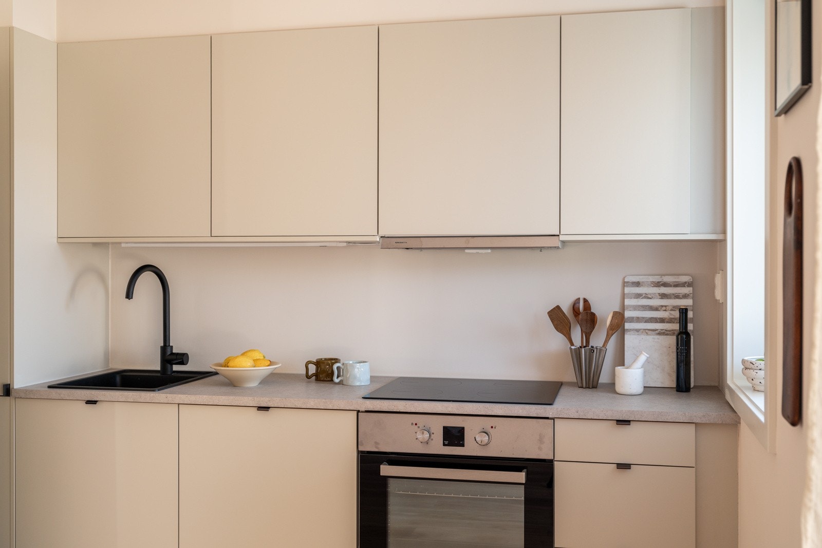 Stilrent og moderne kjøkken med glatte fronter i en lys delikat farge. Innredningen har laminert benkeplate med nedfelt sort oppvaskkum og sort armatur. Praktisk med belysning under overskap. Galleribilde