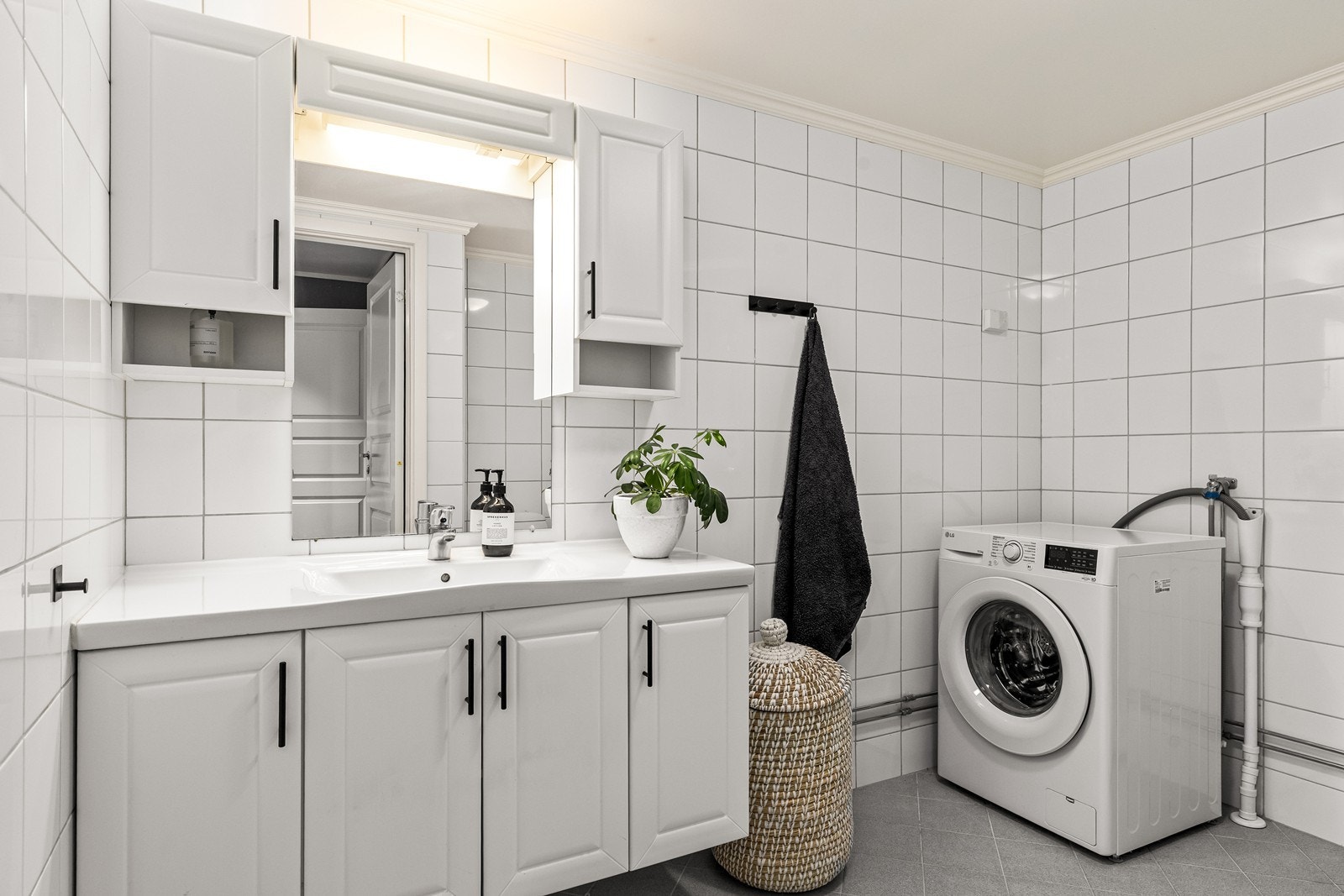 Flislagt bad med opplegg for vaskemaskin og god oppbevaring i servantinnredningen. Galleribilde