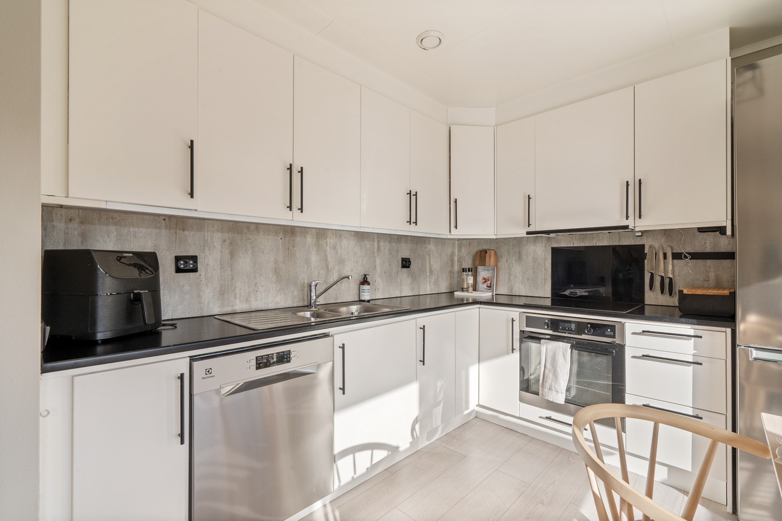 Moderne detaljer med sorte håndtak, stikkontakter og "backsplash i betong-look". Galleribilde