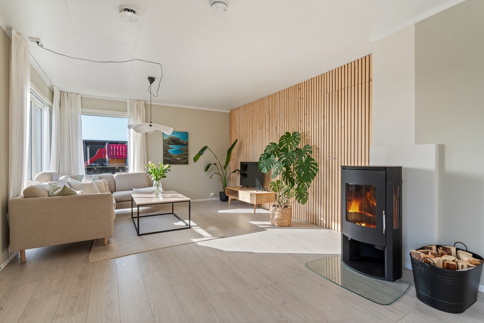 Innbydende stue med tidsriktige farger, flott spilevegg og vedovn som bidrar til en varm og hyggelig atmosfære. Galleribilde