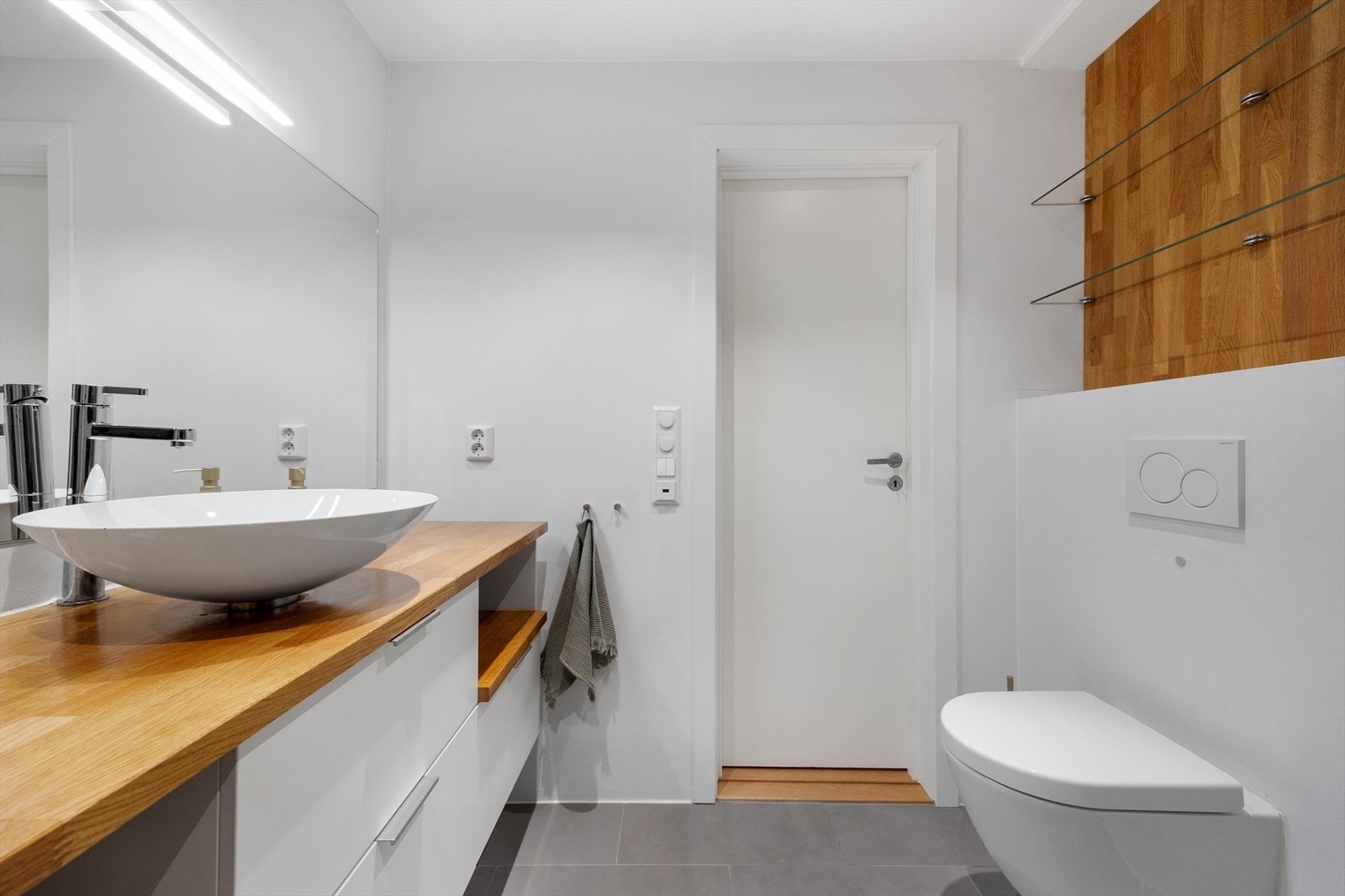 Baderommet er innredet med vegghengt toalett, dusj og servant møblement med speil. Her er der også varmekabler i gulv og opplegg til vaskemaskin. Galleribilde