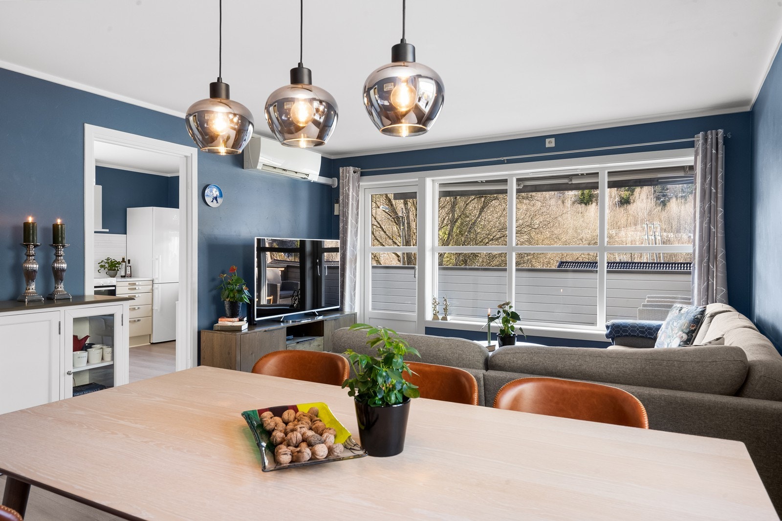 Store vindusflater gir rikelig naturlig lys og gjør stuen til et innbydende samlingspunkt Galleribilde