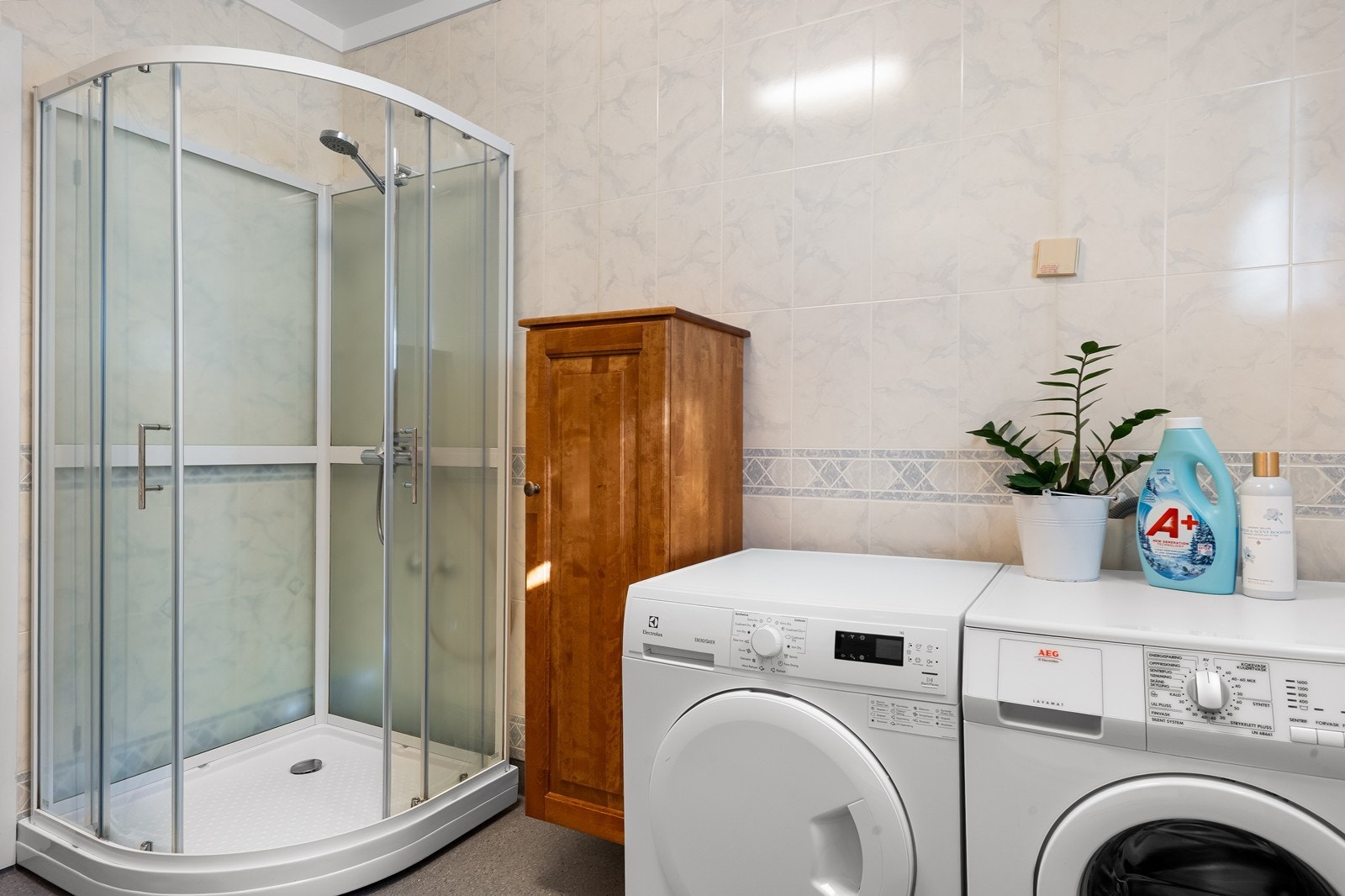 Badet har dusjkabinett med glassdører, i tillegg til opplegg og plass for både vaskemaskin og tørketrommel. Galleribilde