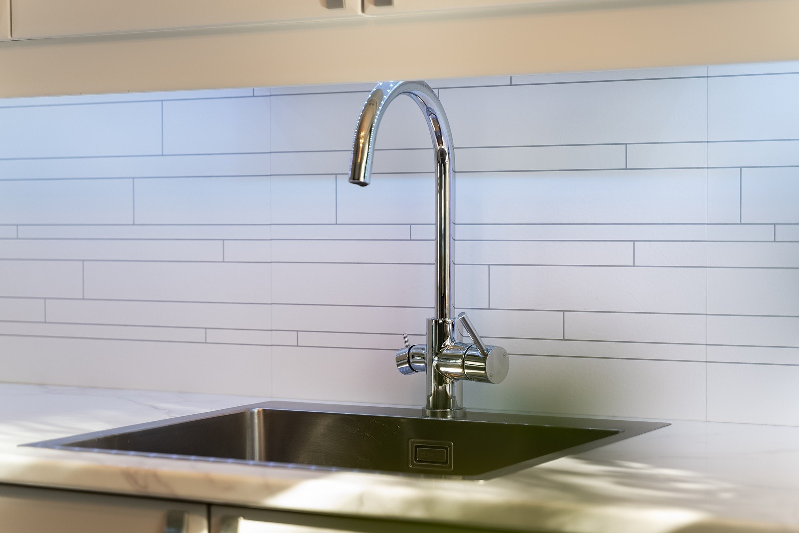 Kjøkkenvasken av rustfritt stål, er nedsenket i benkeplaten og inneholder vaske- og skyllekum. Galleribilde