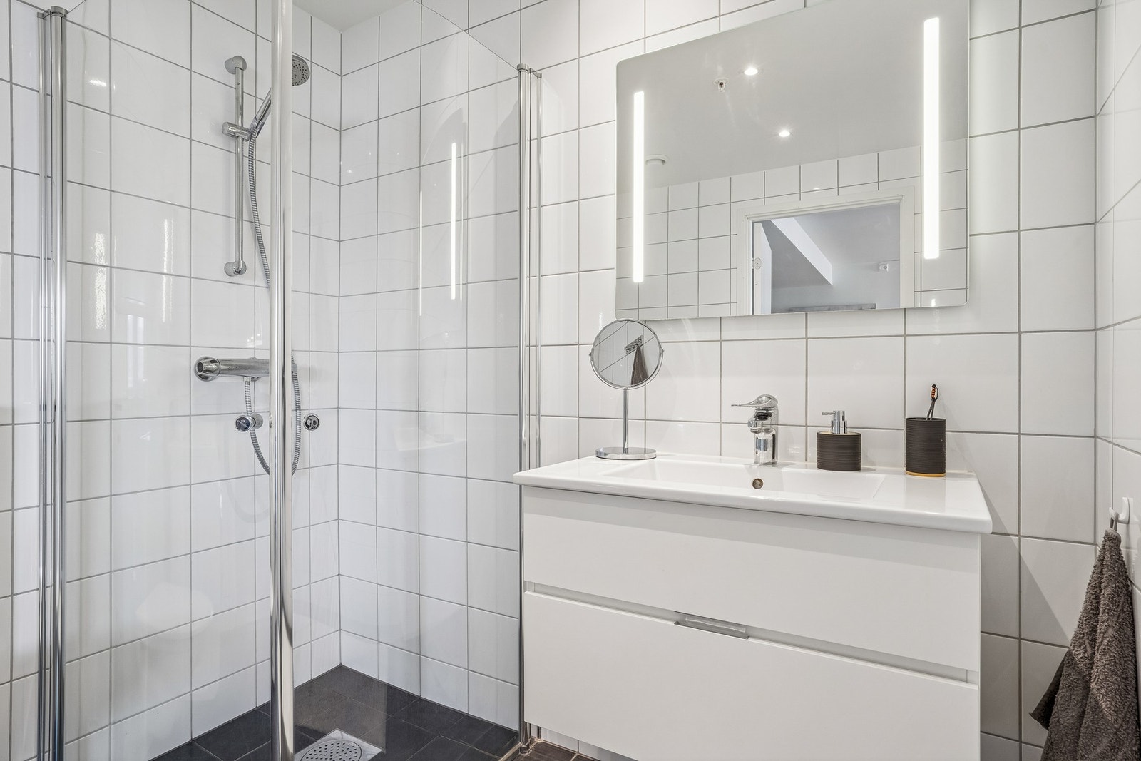 Funksjonelt bad med moderne flislagte overflater, som gir et tidløst og delikat uttrykk. Galleribilde