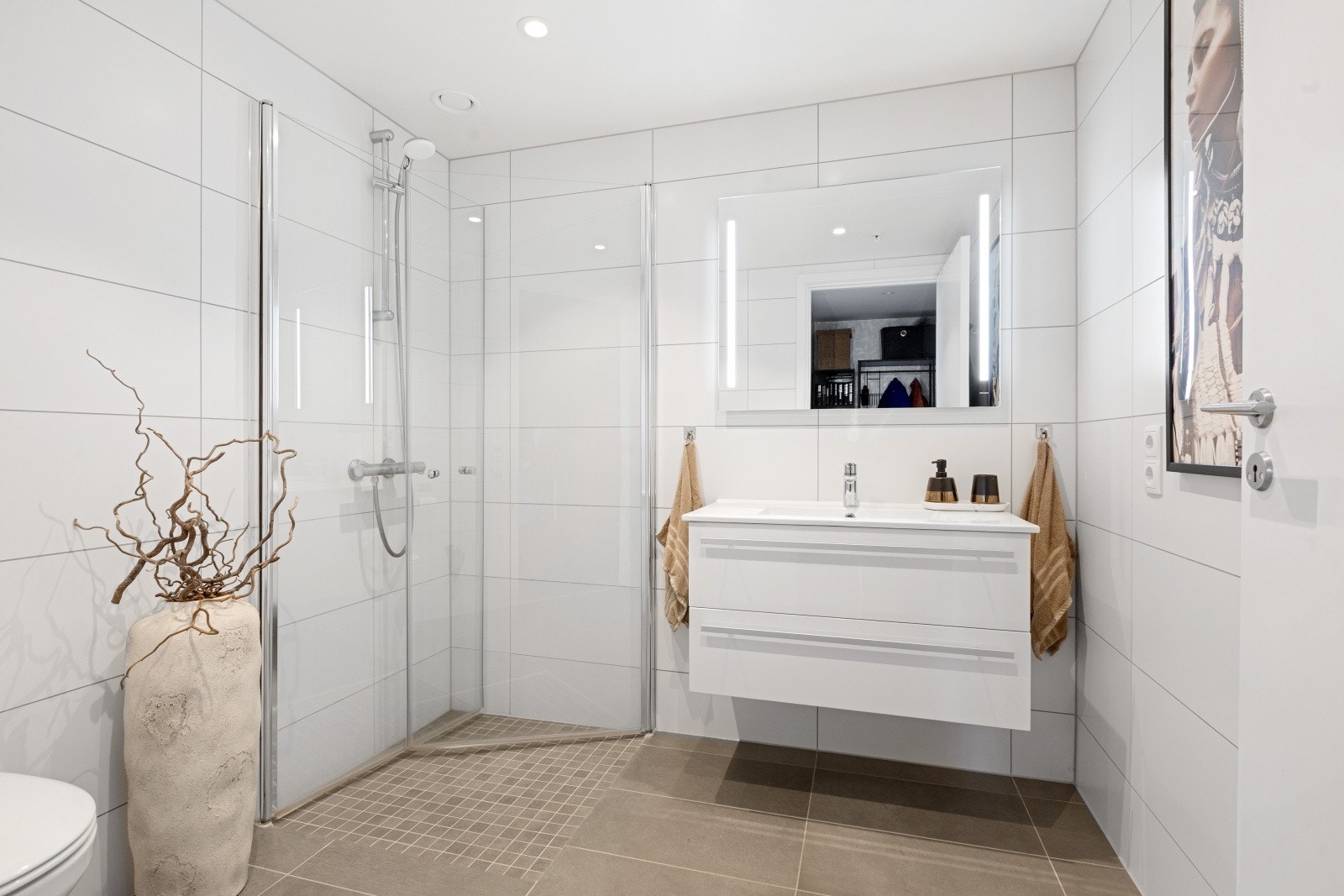 Baderommet er innredet med hvit baderomsinnredning, dusjhjørne med innfellbare dusjvegger og speil med belysning. Galleribilde