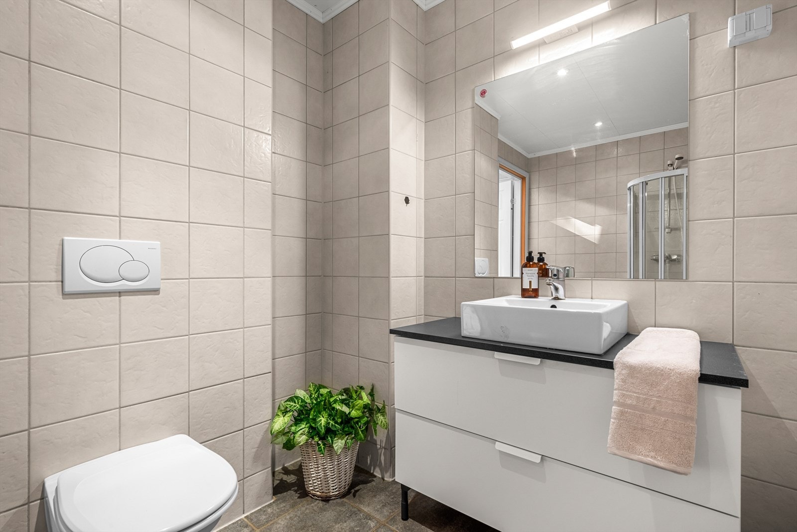 Rommet har fliser på både gulv og vegger, og ble oppgradert med nytt dusjkabinett i 2024. Galleribilde