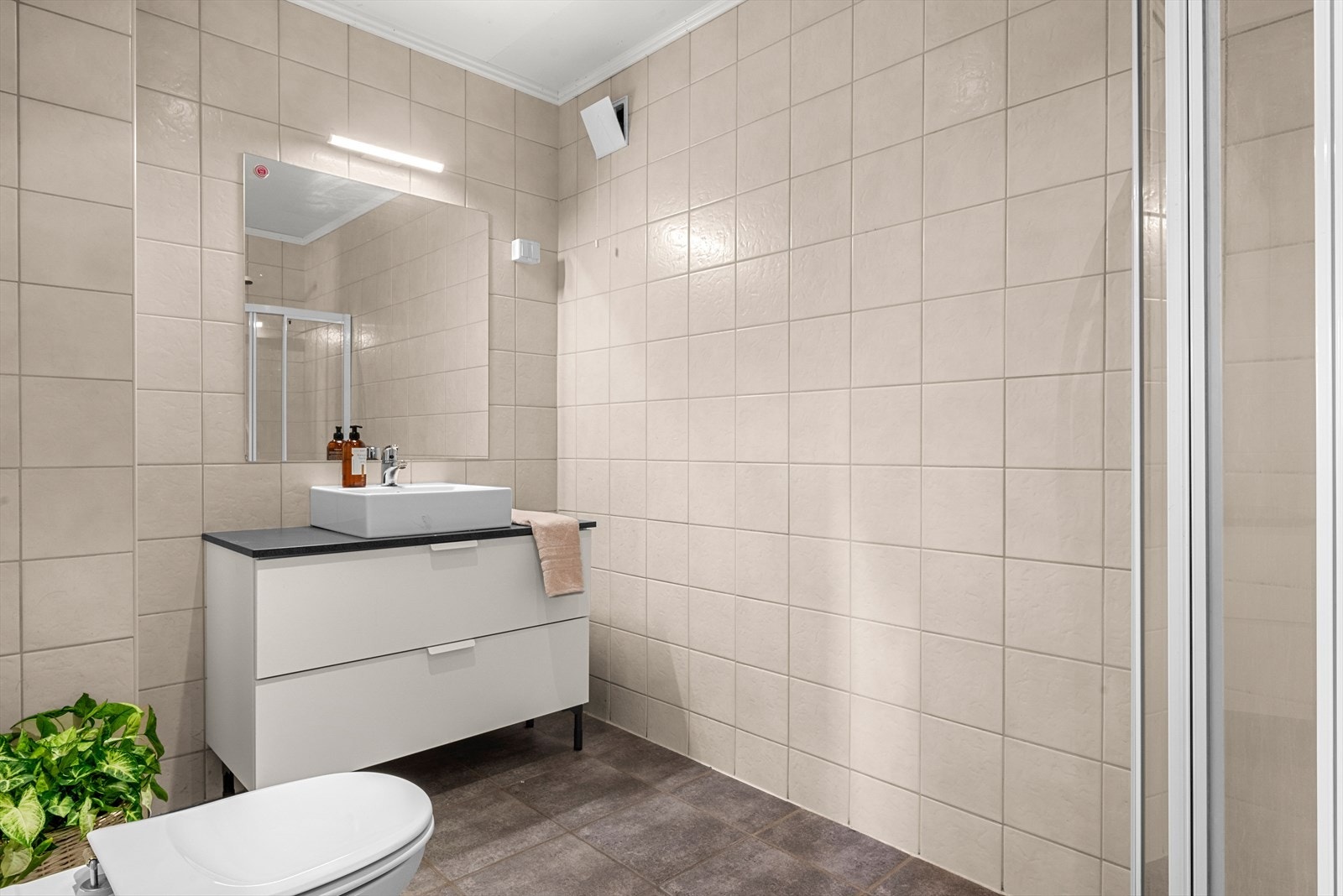 Boligens andre bad ligger i underetasjen og er utstyrt med dusjhjørne, veggmontert toalett, servant i skap, mekanisk avtrekk og elektrisk gulvvarme for økt komfort. Galleribilde