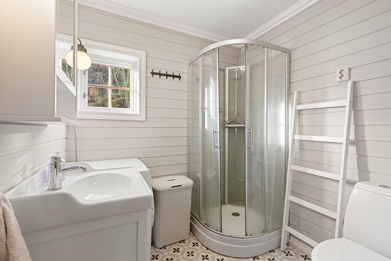 Bad 2 med flislagt golv med varmekablar og panel på vegg. Dette badet er innreda med nedfelt servant, toalett, dusjkabinett og opplegg for vaskemaskin Galleribilde