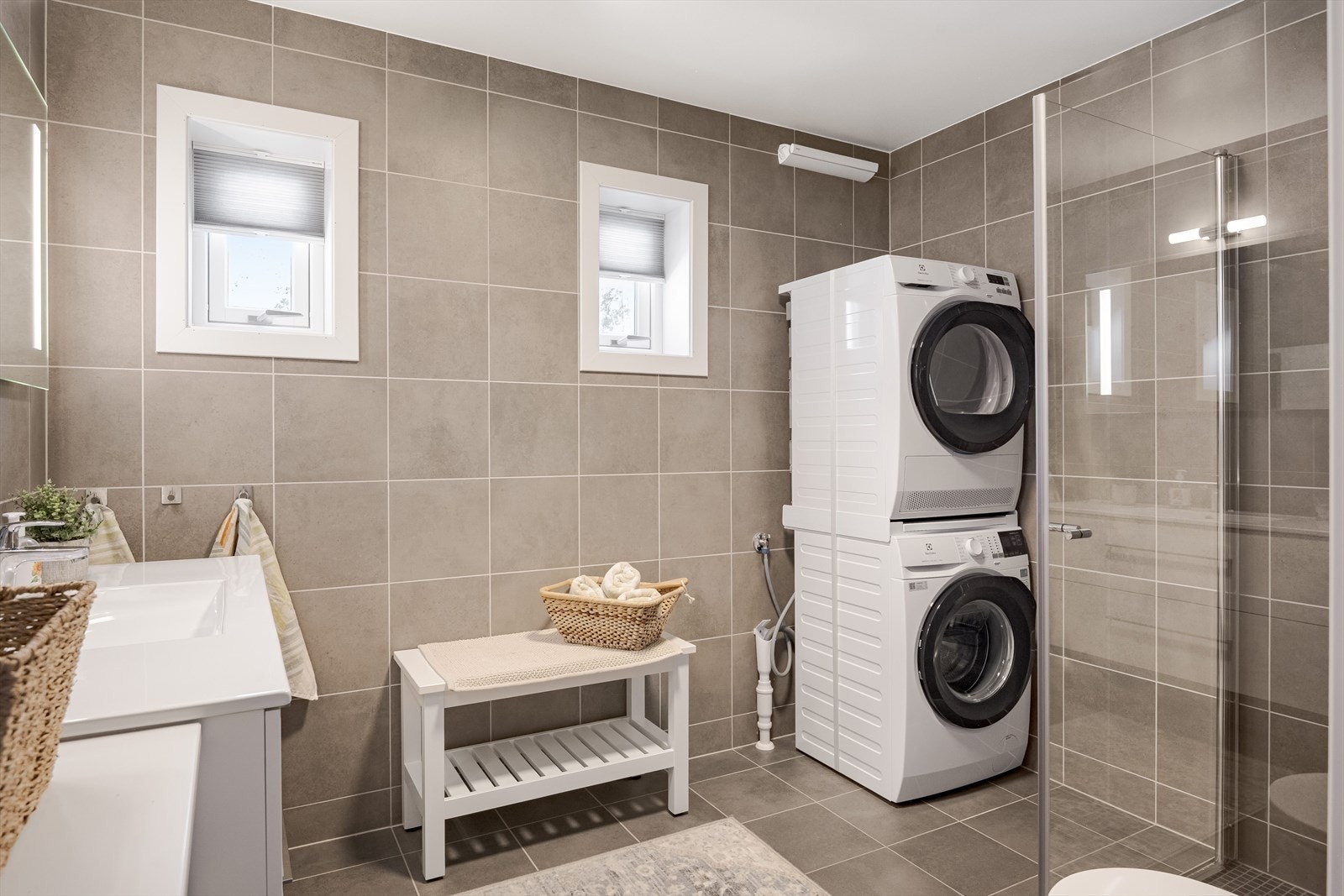 Baderommet har moderne fliser på gulv og vegger, vannbåren gulvvarme, downlights i himlingen og avtrekk via balansert ventilasjon. I hjørnet er det plass og opplegg for vaskemaskin, samt tørketrommel over om ønskelig. Galleribilde