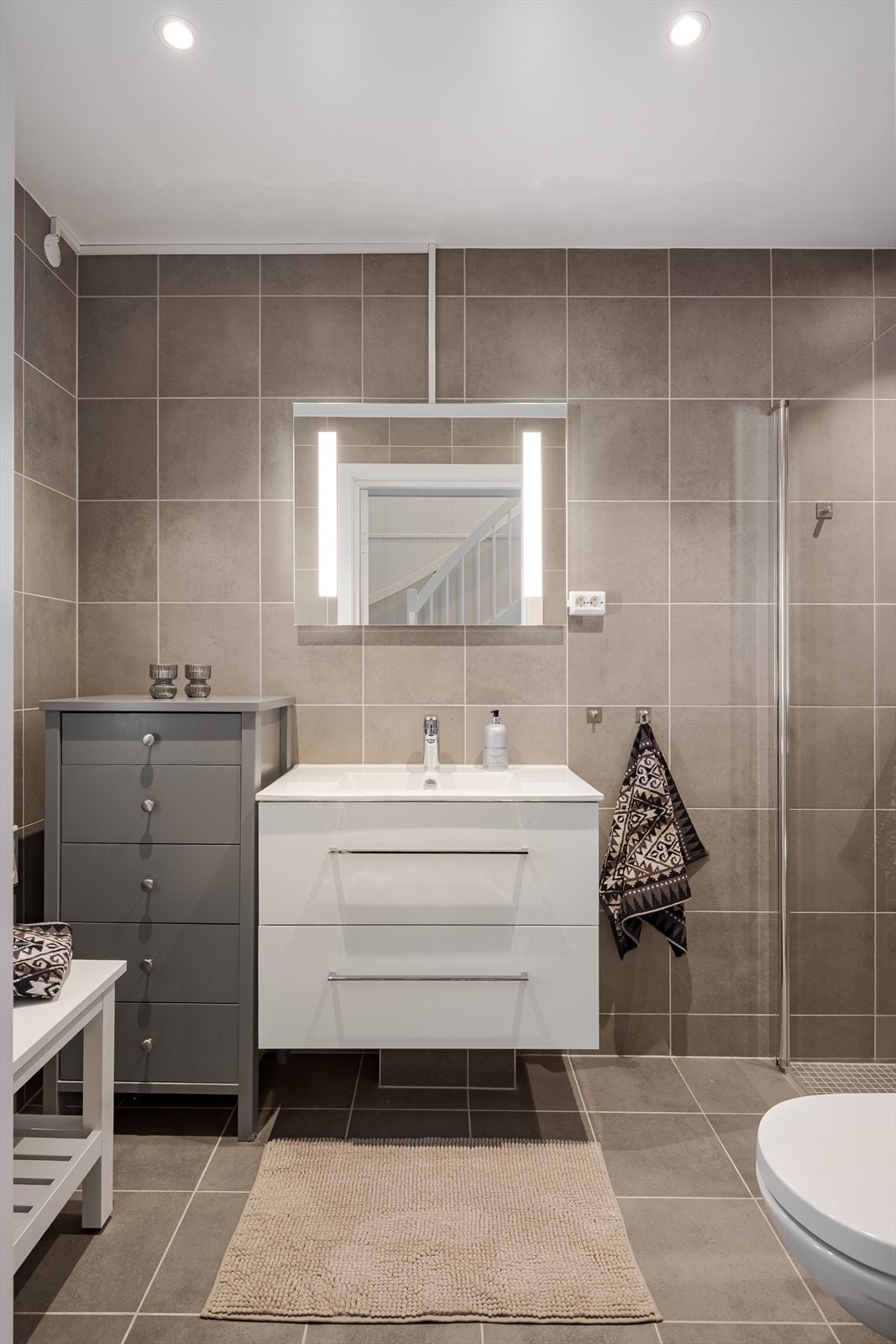 Fra entréen har du adkomst til baderom 1 som er et flott flislagt baderom fra byggeåret 2024. Baderommet har fliser på gulv og vegger, vannbåren gulvvarme, downlights i himlingen og avtrekk via balansert ventilasjon. Galleribilde