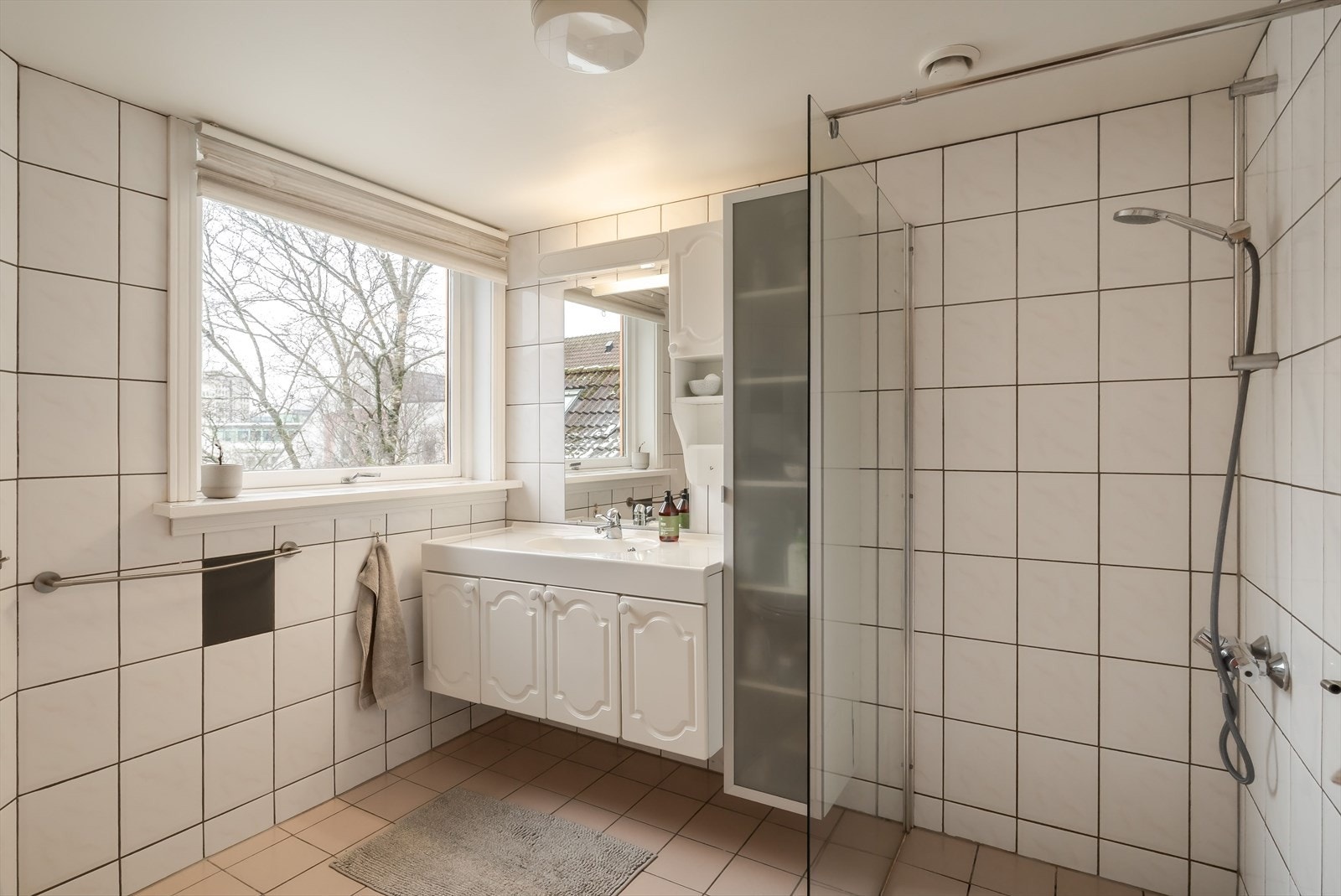 Stort og godt helfliset bad med varme i gulv | Dusjnisje, servant i møbel og toalett Galleribilde