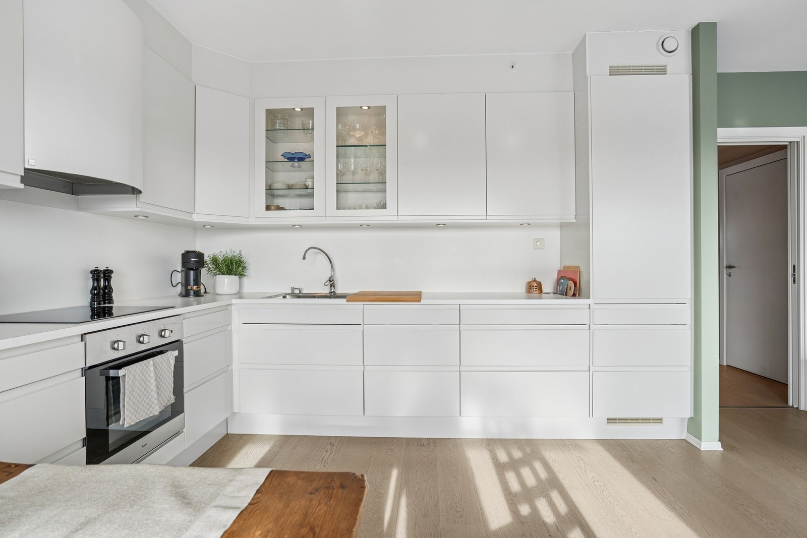 Stilrent kjøkken med innredning av glatte fronter og benkeplate av laminat. Det er kjøkkenventilator med avtrekk ut. Galleribilde