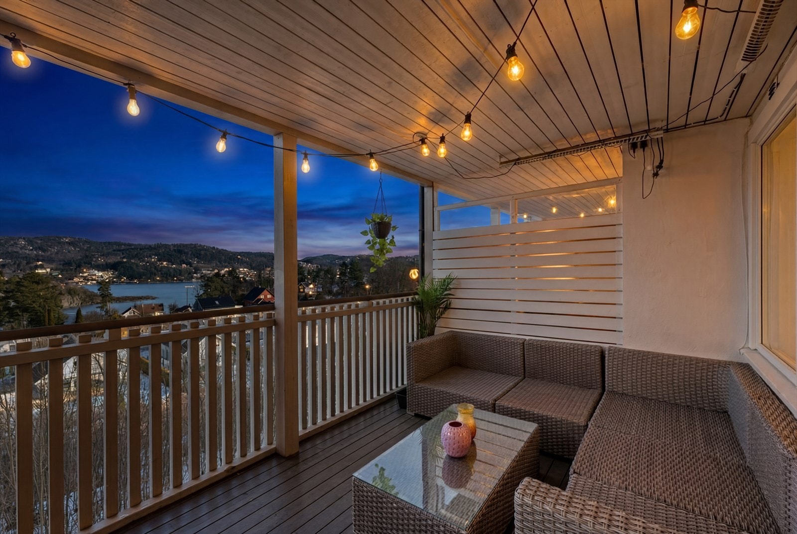 Romslig og overbygget veranda mot øst, utvidet i regi av borettslaget ca. 1997. Bildet er redigert for å fremheve stemningen på kveldstid. Faktiske lysforhold kan variere. Galleribilde