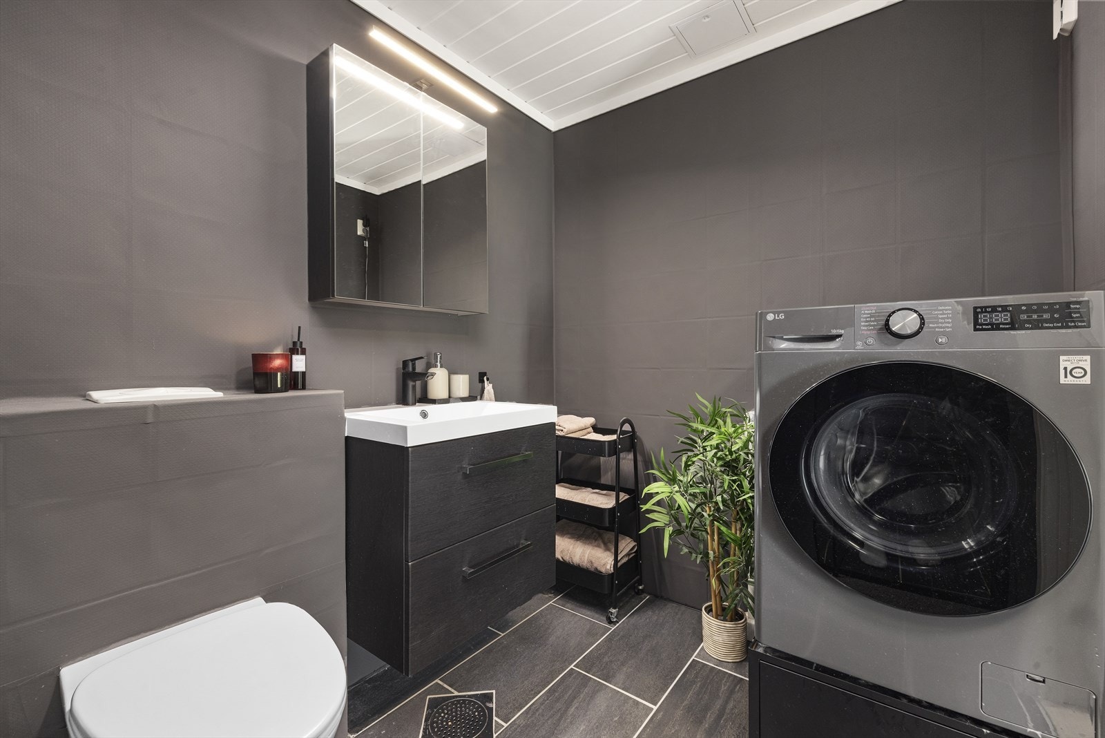 Badet har varmekabler i gulv, veggmontert toalett og pen servantinnredning, samt romslig dusjnisje og opplegg for vaskemaskin. Nytt dusjsett og skyvedør til dusj i 2025. Galleribilde