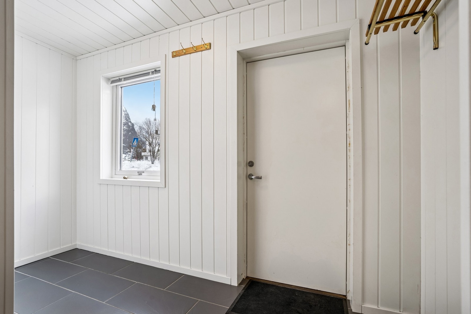 Flislagt entrè med plass til å henge fra seg yttertøy og legge fra seg sko. Galleribilde