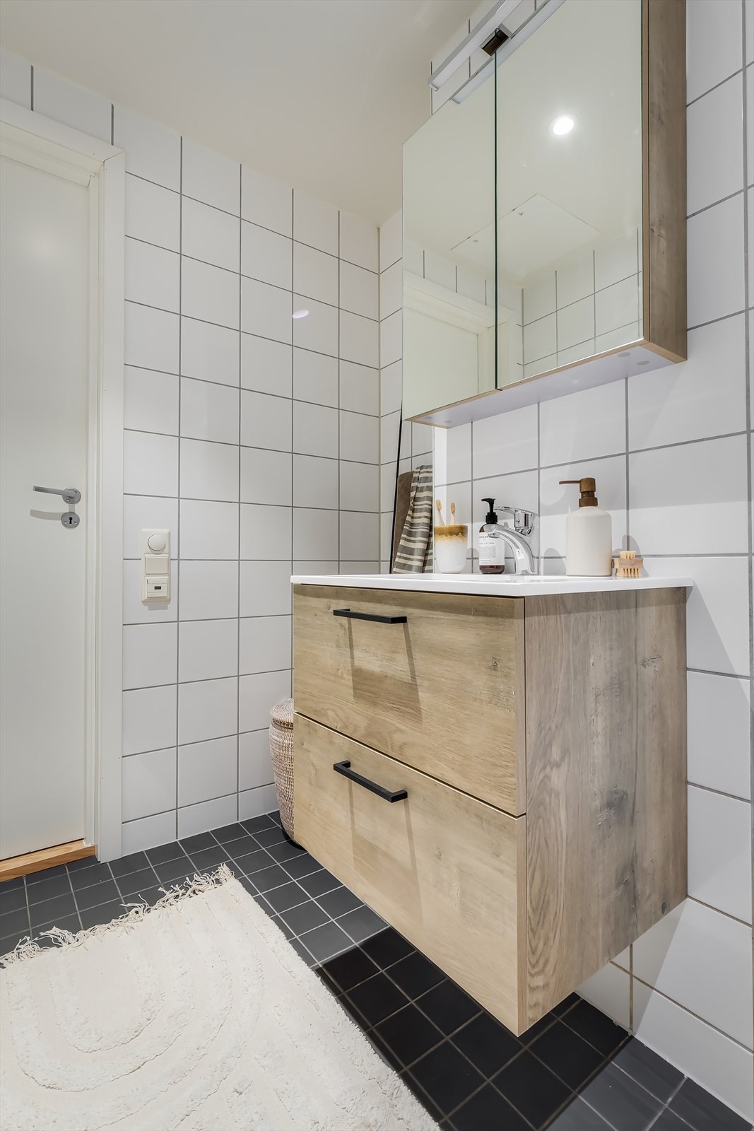 Badet er innredet med nedfelt servant med underskap, speilskap, vegghengt toalett og dusjplass med inn- og utadslående dusjvegger. Galleribilde