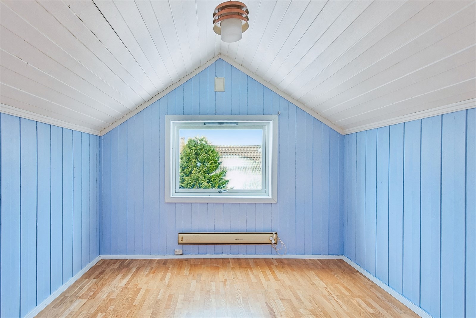 Det ene av to soverom i andre etasje, med sjarmerende skråtak og malt panel. Galleribilde