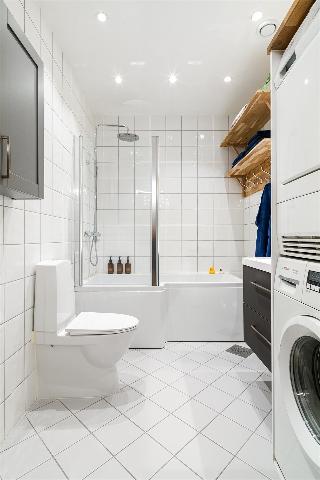 Helfliset bad/vaskerom med varme i gulv og spotter i tak. Badekar med dusj, wc og vask i seksjon. Galleribilde