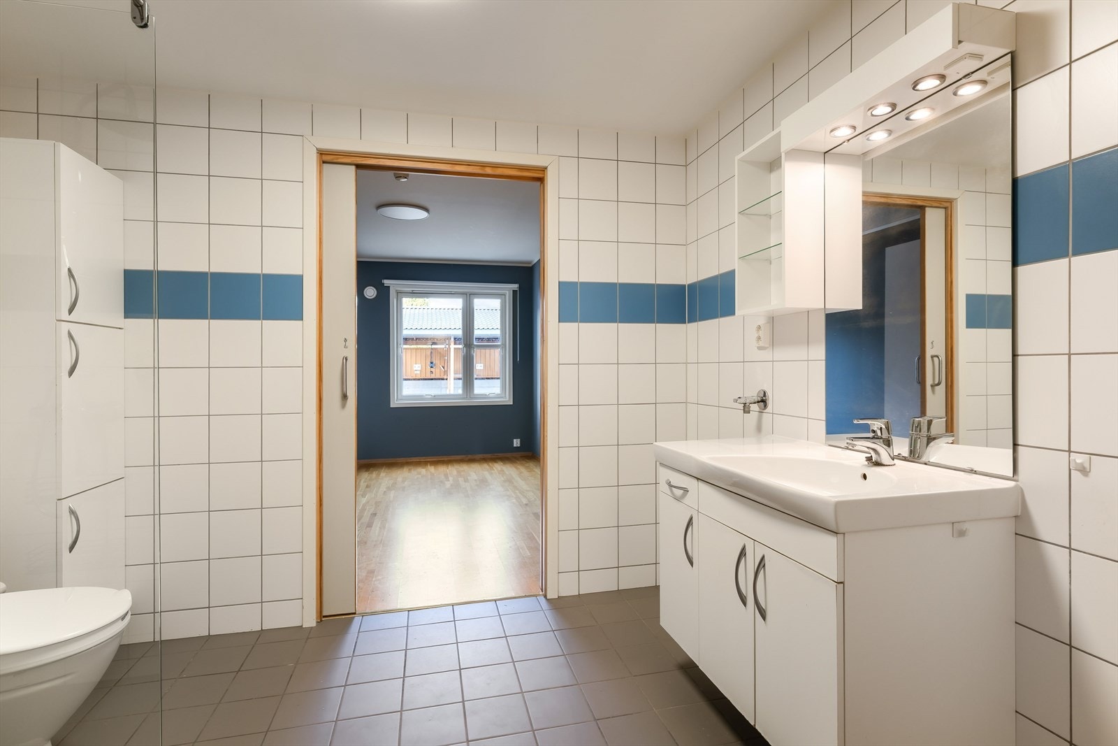 Rommet er innredet med toalett, servant i en lys innredning, godt med skap, speil og opplegg for vaskemaskin. Herfra har man en praktisk adkomst med skyvedør til soverom. Galleribilde