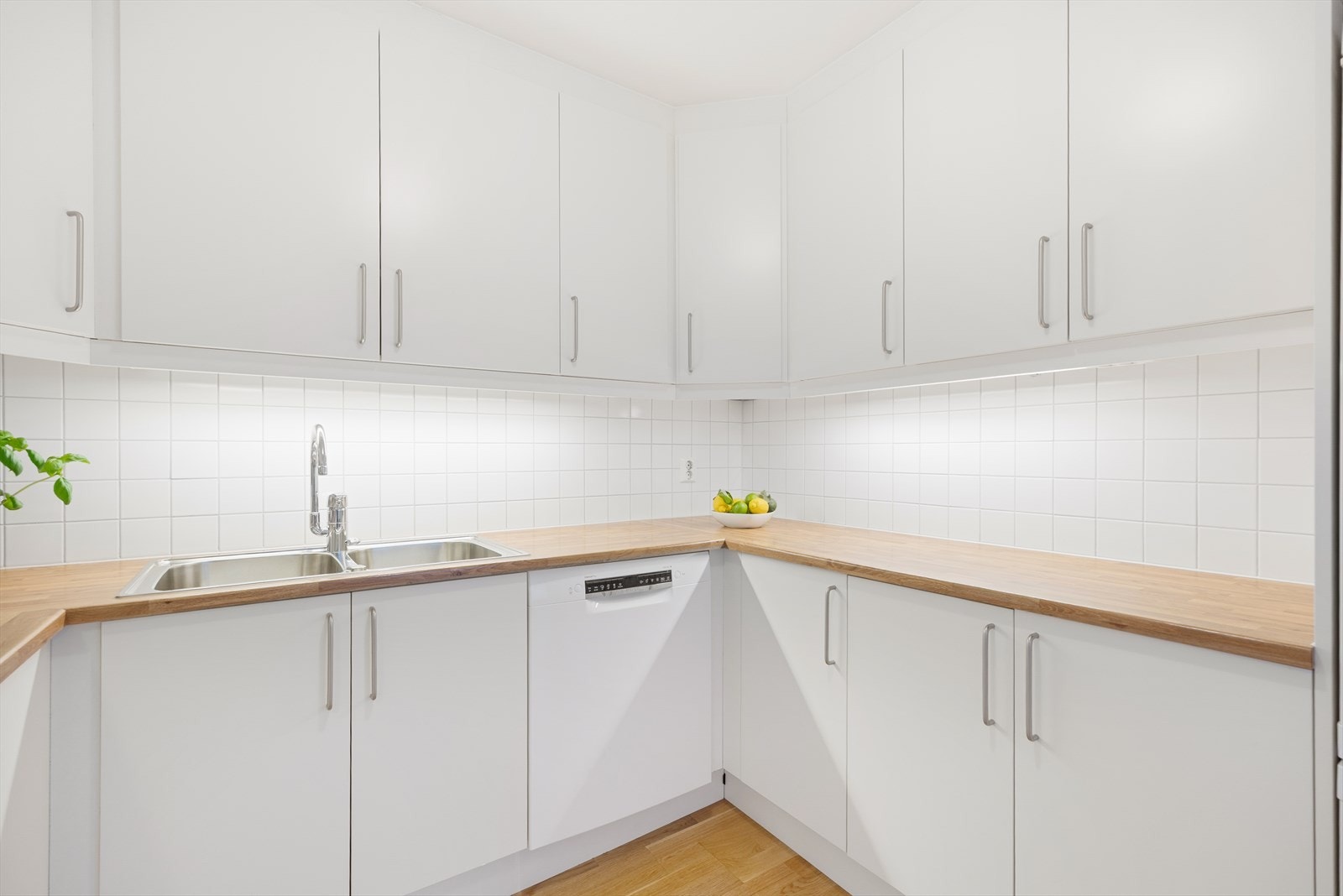 Flis på vegg over laminat benkeplate med gode arbeidsflater, nedfelt platetopp og dobbel oppvaskkum i rustfritt stål. Galleribilde